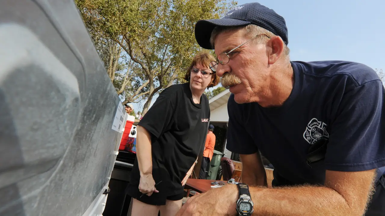 Homeowners talking with a worker beside a damaged house