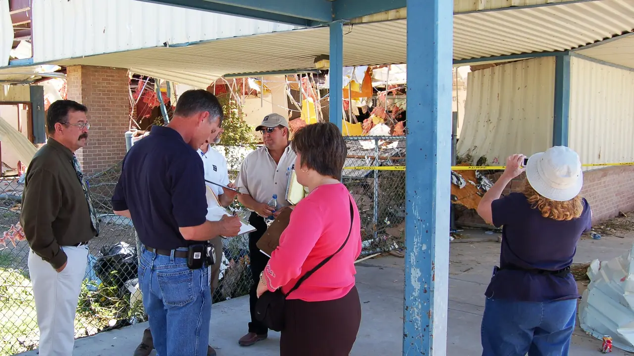 Inspector talking with residents outside a damaged home